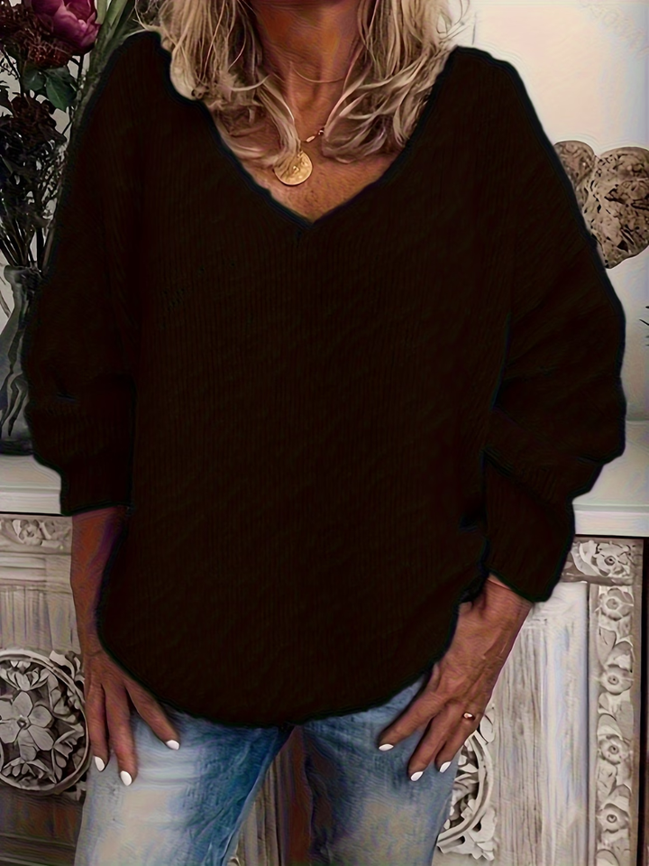 Grobstrickpullover in Schwarz an einer Frau mit goldener Medaillon-Kette, leicht kontrastreich fotografiert, gerippte Struktur an Ärmeln und Saum. 3