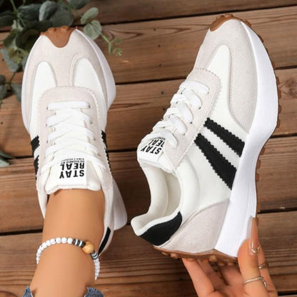Weiße Sneaker mit schwarzen Streifen und hellem Wildleder, einer in der Hand, Blick auf Schnürung und Seite 10