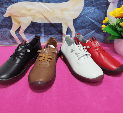 Vier Paar Freizeitschuhe in Schwarz, Braun, Weiß und Rot auf rosa Hintergrund mit Blumen.