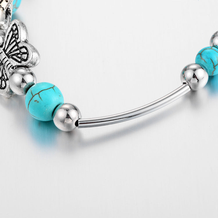 Armband mit türkisfarbenen Perlen, Schmetterlingsanhänger, silberne Akzente, Modeschmuck.