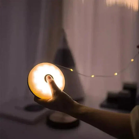 Hand hält runde LED-Lampe, warmweißes Licht, dimmbar, tragbar, Nachtbeleuchtung.