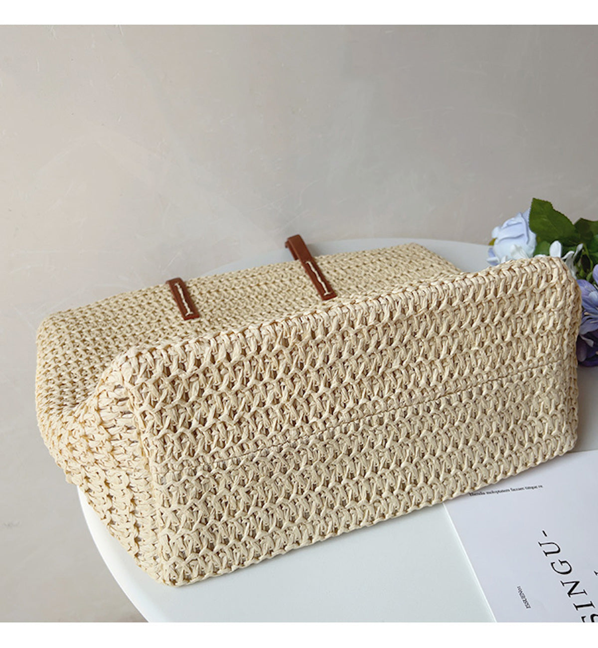 Geflochtene Strohtasche beige, rechteckig, auf weißem Tisch, Sommermode Accessoire.