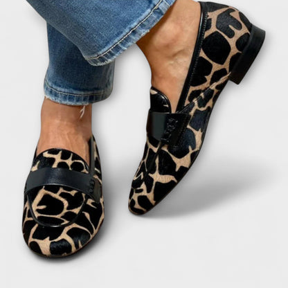 Beide Loafer von vorn und von der Seite am Fuß, das Giraffenmuster, die schwarze Spange und der flache Absatz sind gut zu sehen. 3