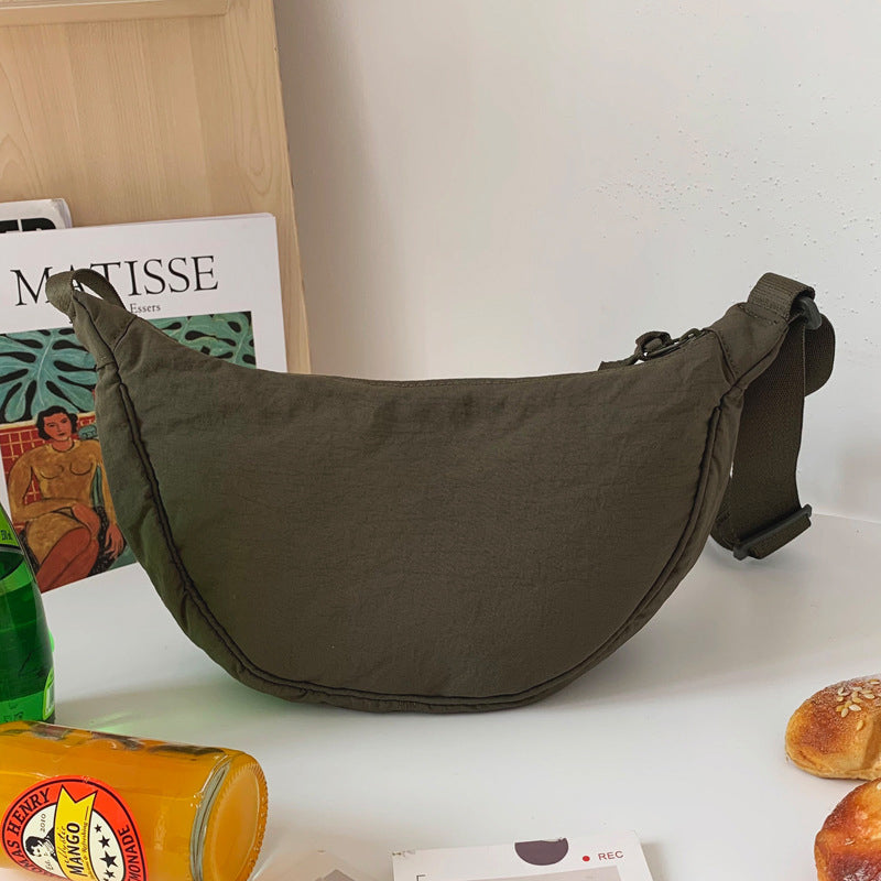 Olivgrüne Umhängetasche aus Stoff auf Tisch, modisch, praktisch, ideal für Alltag und Reisen.