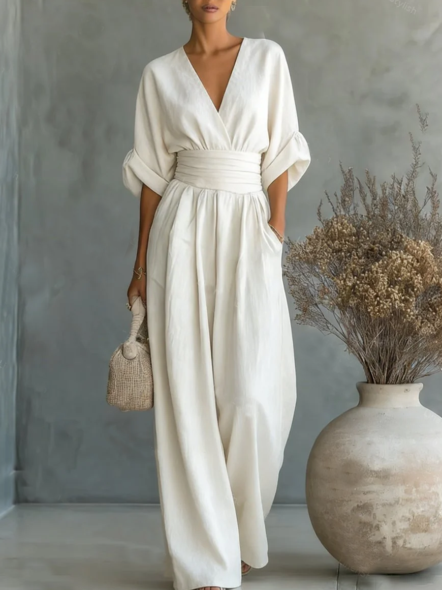 Model in cremeweißem Jumpsuit mit V-Ausschnitt und weitem Bein, Hand in der Tasche, neben einer Vase 1