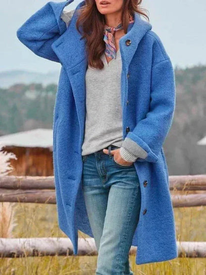 Mantel in Blau mit Kapuze und Knopfleiste, zu grauem Pullover, Halstuch und Jeans getragen, Hand in der Hosentasche. 4