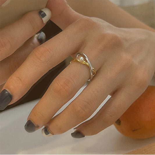 Damenhand mit silbernem und goldenem Ring, Perlendetail, stilvoller Schmuck, Nahaufnahme.