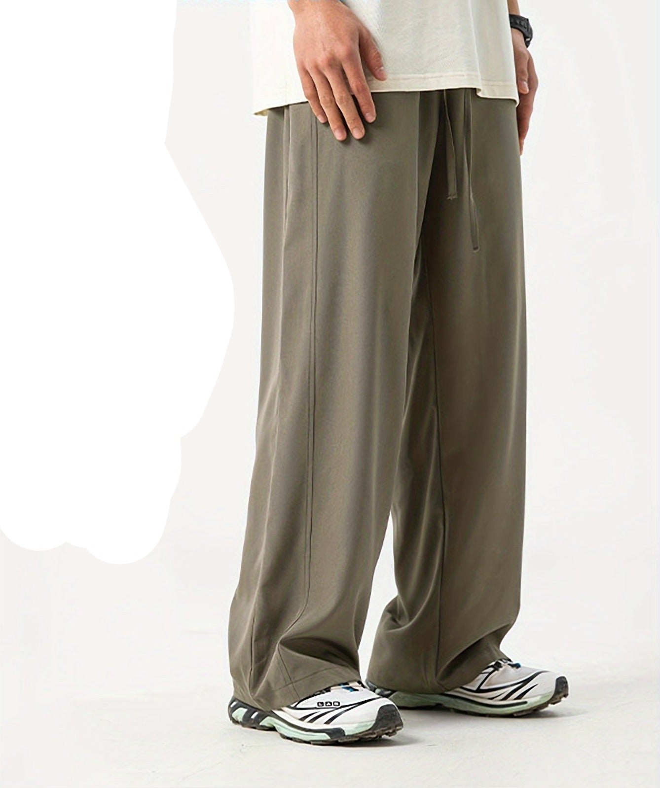 Beige Herren-Jogginghose, locker geschnitten, aus Baumwolle, kombiniert mit weißen Sportschuhen.