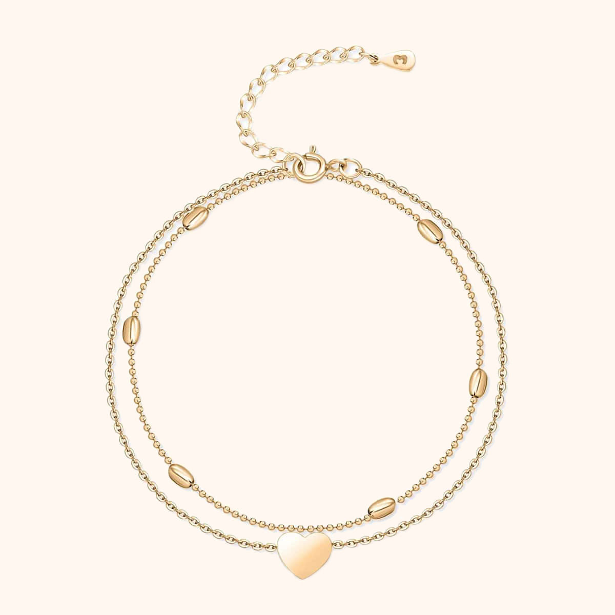 Zweireihiges goldfarbenes Armband mit Herzanhänger und ovalen Details, verstellbar.