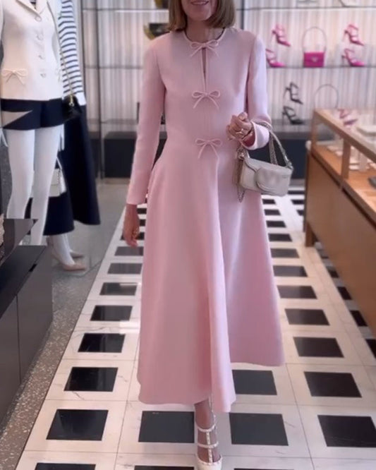Frau in rosa Kleid mit Schleifen, silberne Handtasche, modisches Outfit, elegante Modeboutique.