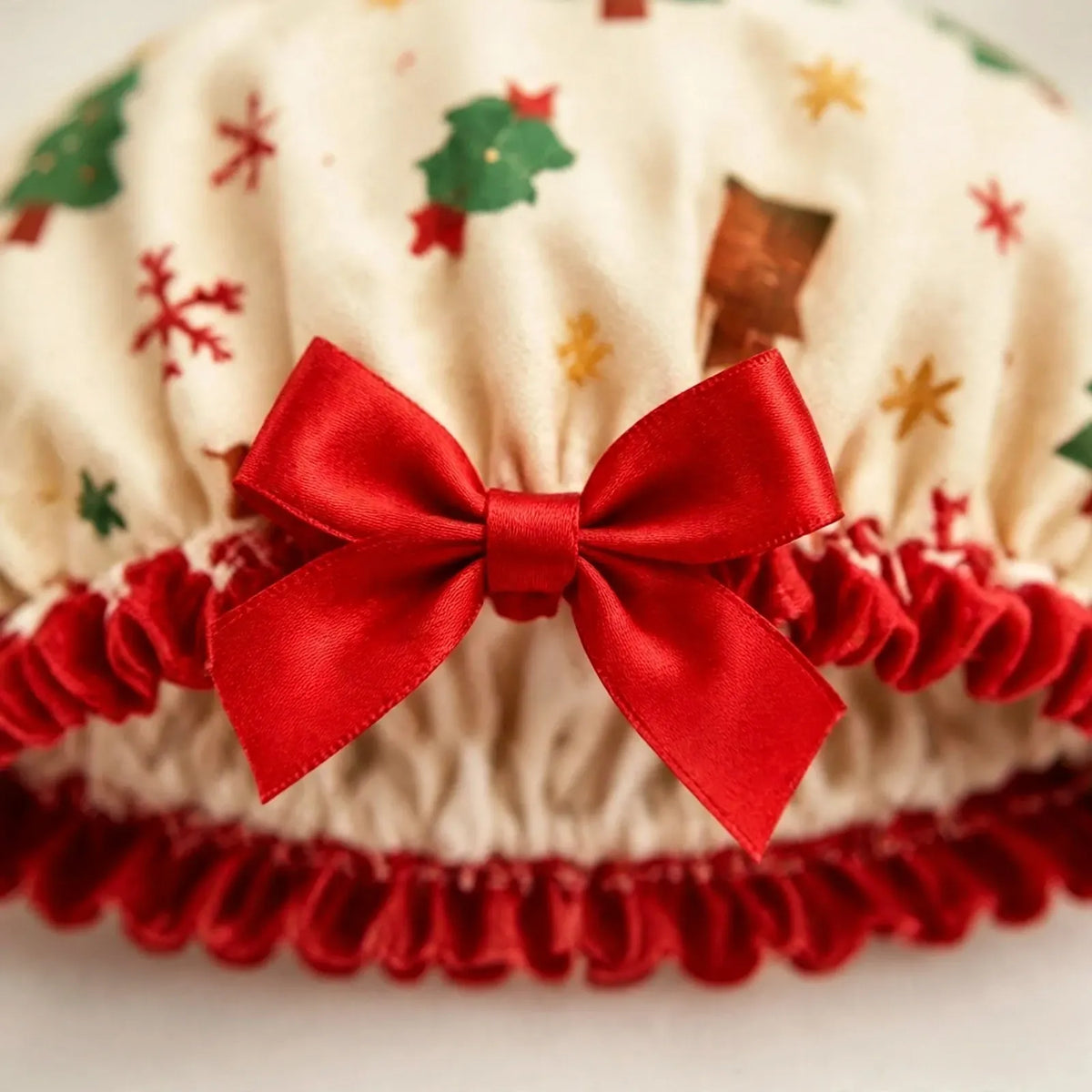 Nahaufnahme der cremefarbenen Duschhaube mit Weihnachtsmotiven, roter Satinschleife und rotem Rüschenrand 3