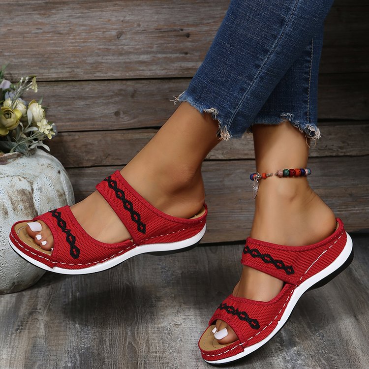 Rote Damen-Sandalen mit Kettenmuster, bequem, lässig, Sommermode, Jeanshintergrund.