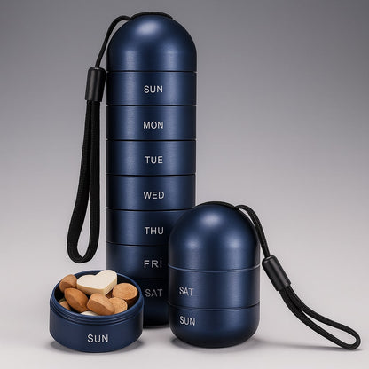 Dunkelblauer Pillenorganizer mit schwarzer Schlaufe: hoher Stapel, kurzer Stapel und ein geöffnetes Fach mit verschiedenen Tabletten, darunter eine herzförmige. 7