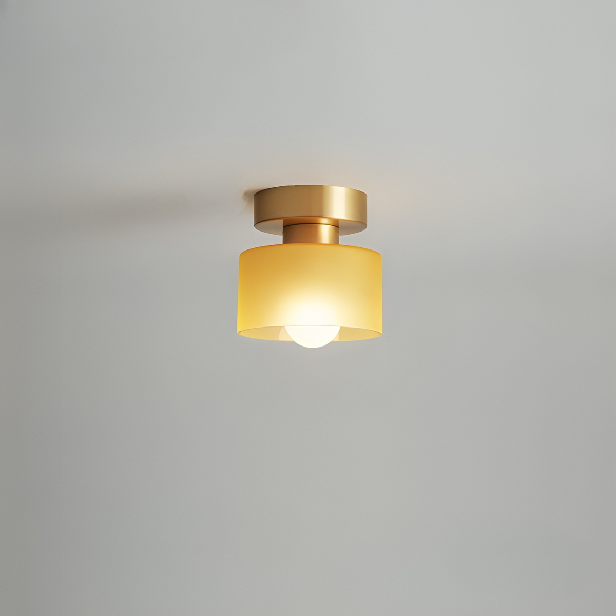 Deckenleuchte mit goldfarbenem Baldachin und gelb-orangem Schirm, der das Licht der Kugelbirne warm streut. 9