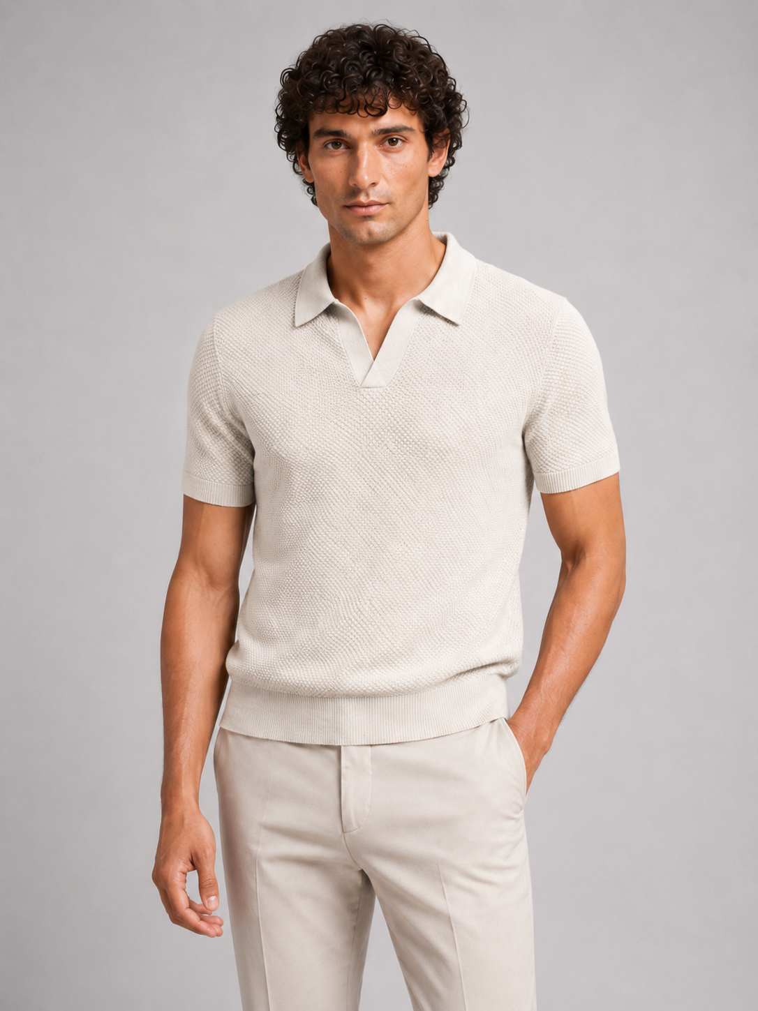 Mann in cremefarbenem Strukturstrick-Poloshirt mit offenem V-Kragen und heller Hose, eine Hand in der Tasche, Halbansicht 16