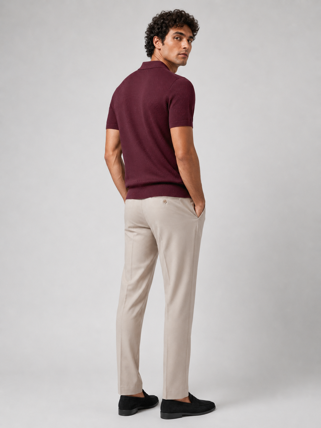 Rückansicht des weinroten Strickpolos, Model blickt über die Schulter, beige Hose, schwarze Loafer 24