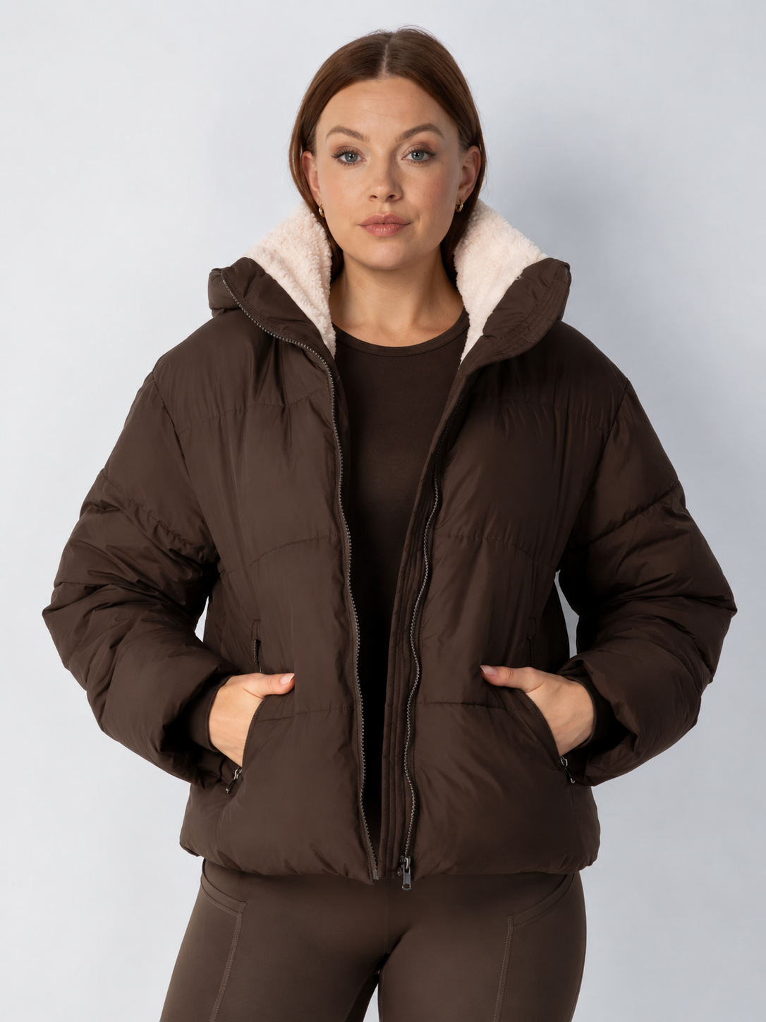Braune Steppjacke offen getragen, heller Teddykragen sichtbar, Hände in den Reißverschlusstaschen 14