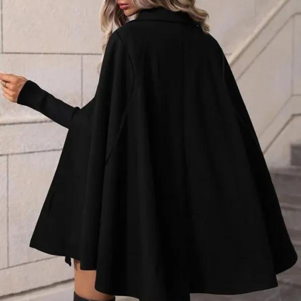 Frau in schwarzem Cape-Mantel, elegantes Design, Herbstmode, Treppenhaus-Hintergrund.