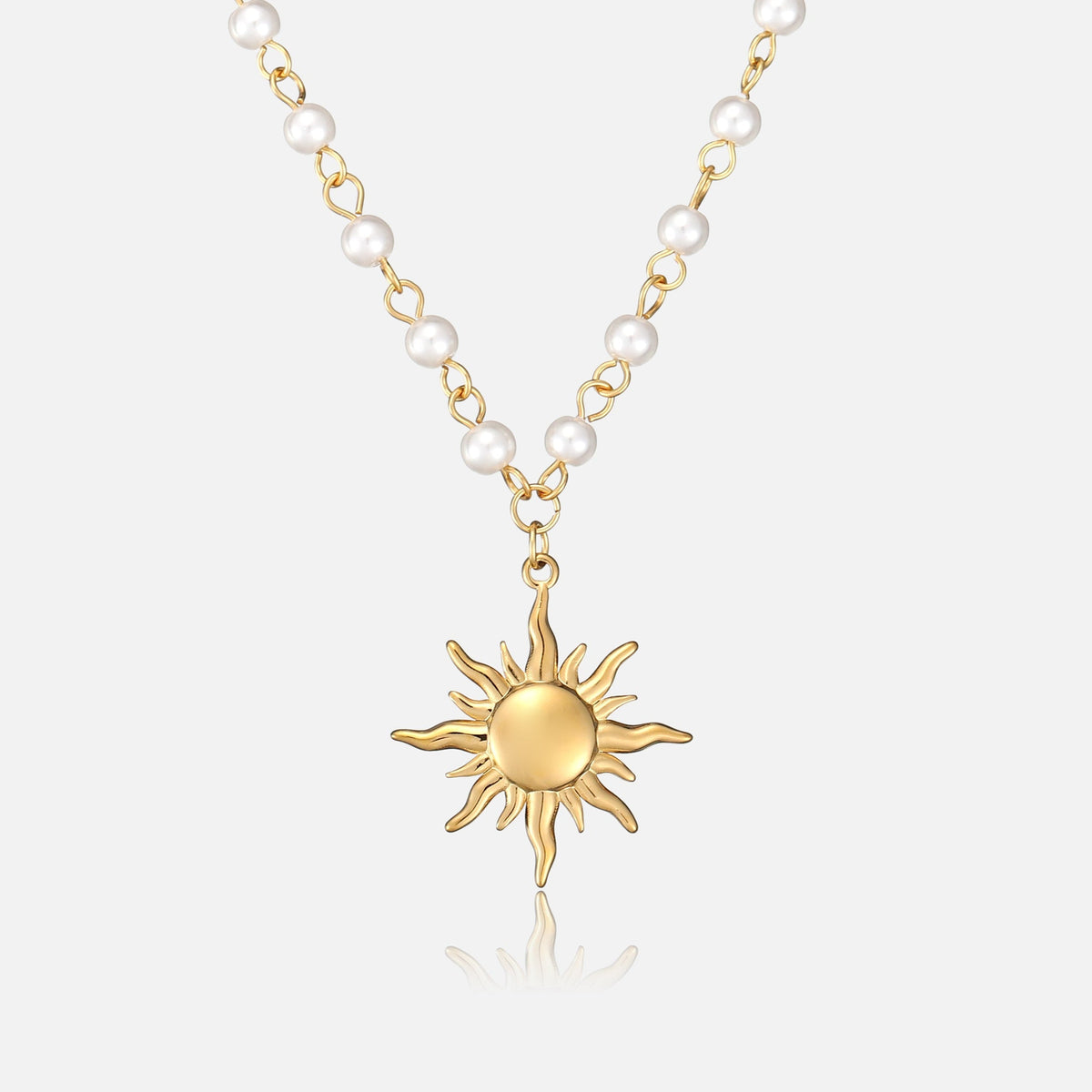 Frontansicht der Halskette: goldener Sonnenanhänger mit geschwungenen Strahlen an einer Kette aus weißen Perlen und goldenen Gliedern vor hellem Hintergrund. 1