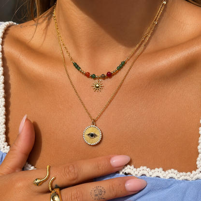 Frau trägt die Perlenkette mit Sonne zusammen mit einer zweiten goldenen Kette mit rundem Augen-Anhänger 3