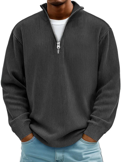 Mann trägt den gerippten Pullover in Anthrazit mit Stehkragen und Reißverschluss, Hände in den Taschen 7