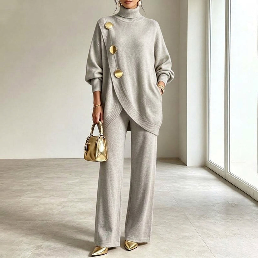 Das Strickset in hellem Grau am Model, asymmetrisch überlappendes Oberteil mit drei goldenen Knöpfen und weit fallende Hose. 3