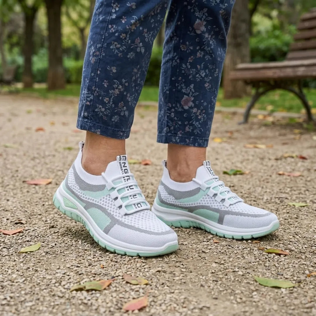 Mintgrüne Mesh-Sneaker an den Füßen einer Frau in blauer Blumenhose vor einer Parkbank 11