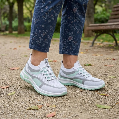 Mintgrüne Mesh-Sneaker an den Füßen einer Frau in blauer Blumenhose vor einer Parkbank 11