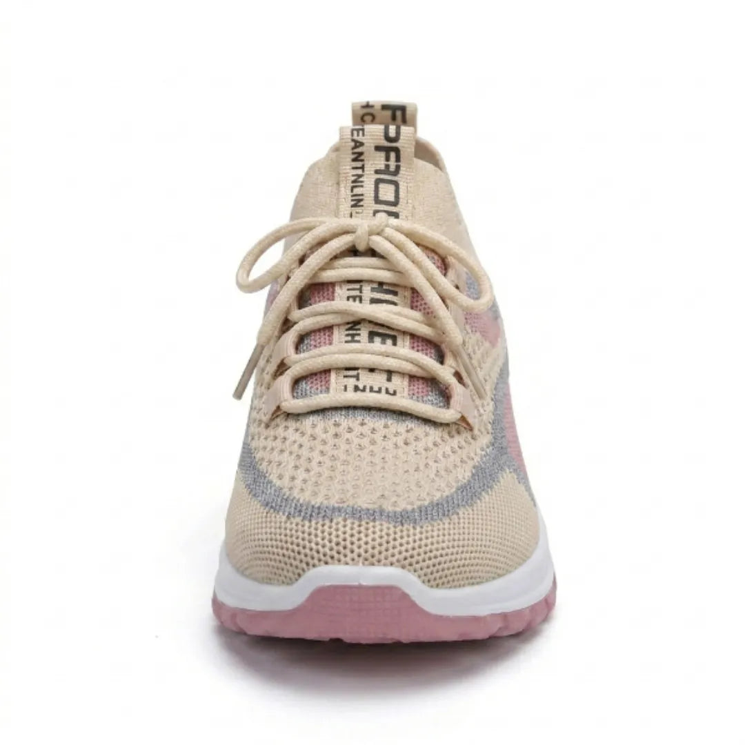 Frontalansicht des beigen Mesh-Sneakers mit Schnürung, rosa Akzenten und bedrucktem Band an der Zunge, rosa Sohle sichtbar. 35