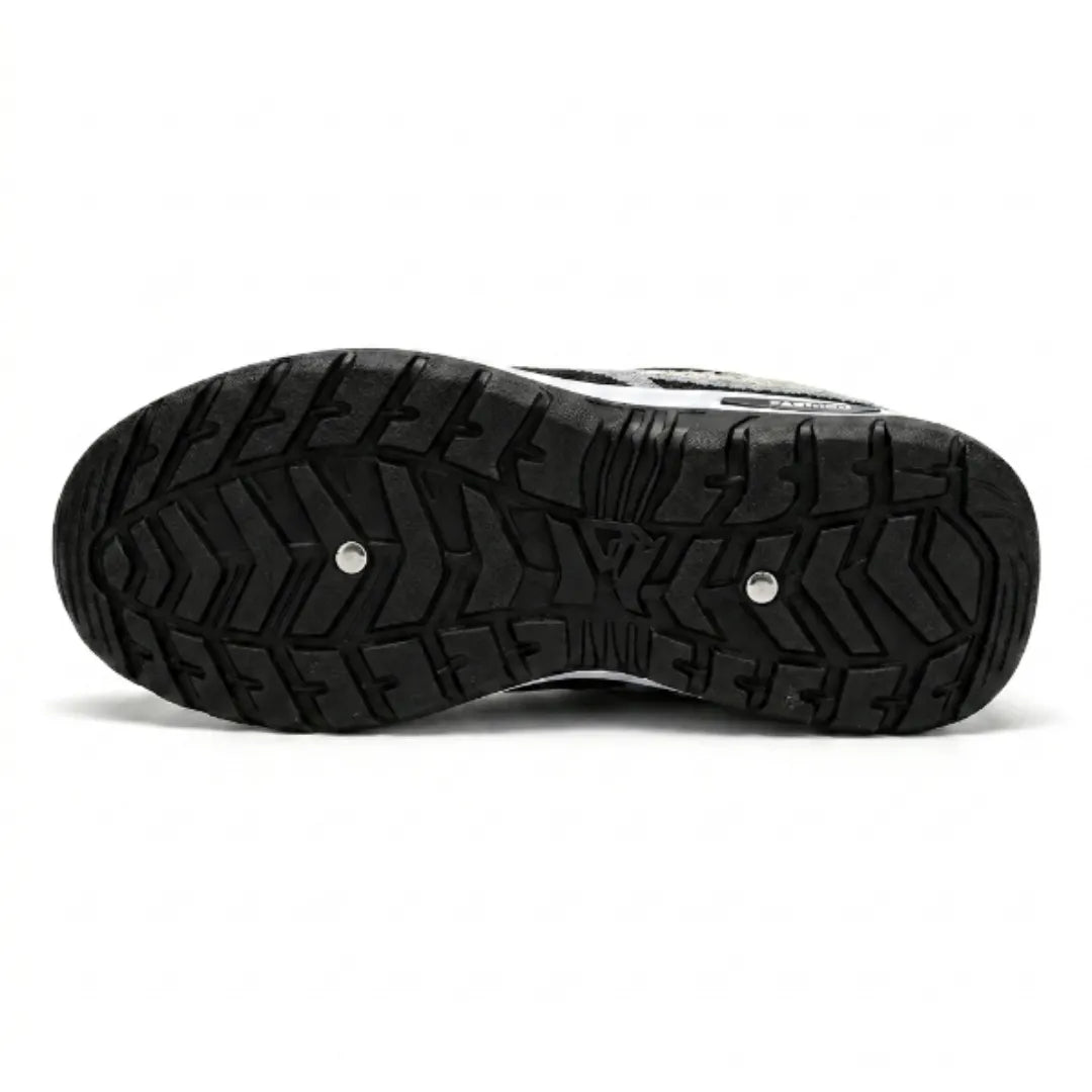 Blick auf die schwarze Gummilaufsohle des Sneakers mit kräftigem Profil aus Zickzack- und Rillenmuster sowie zwei kleinen metallischen Nieten. 45