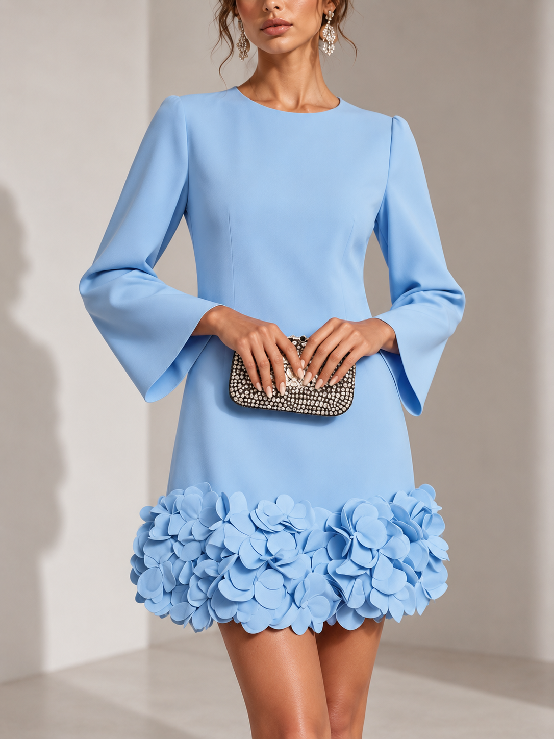 Hellblaues Kleid in der Vorderansicht, getragen mit Strass-Clutch; plastische Blüten am Saum und ausgestellte Ärmel. 5