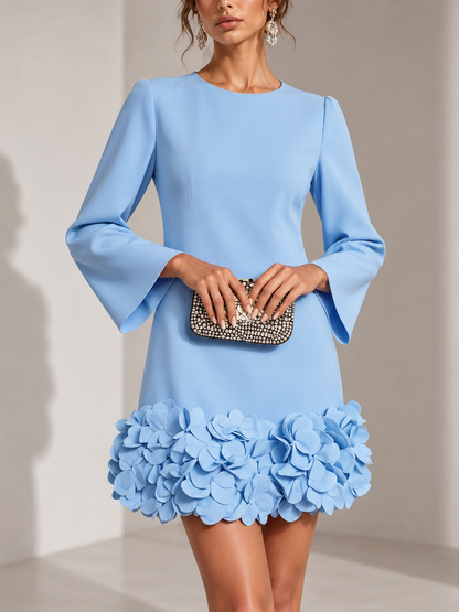 Hellblaues Kleid in der Vorderansicht, getragen mit Strass-Clutch; plastische Blüten am Saum und ausgestellte Ärmel. 5