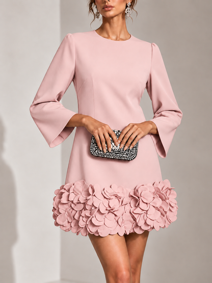 Rosafarbenes Kleid in der Vorderansicht, mit Strass-Clutch kombiniert; dicht gesetzte 3D-Blüten am Saum und weite Ärmel. 9