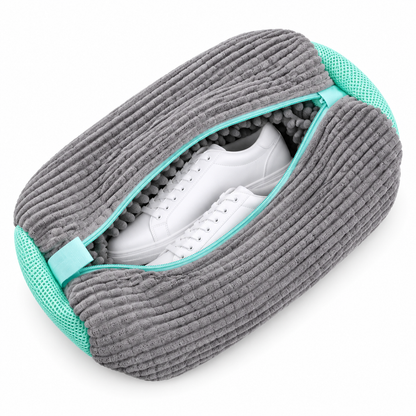 Grauer Waschbeutel aus gerippter Chenille mit türkisen Netzseiten, leicht geöffnet mit weißen Sneakern 10
