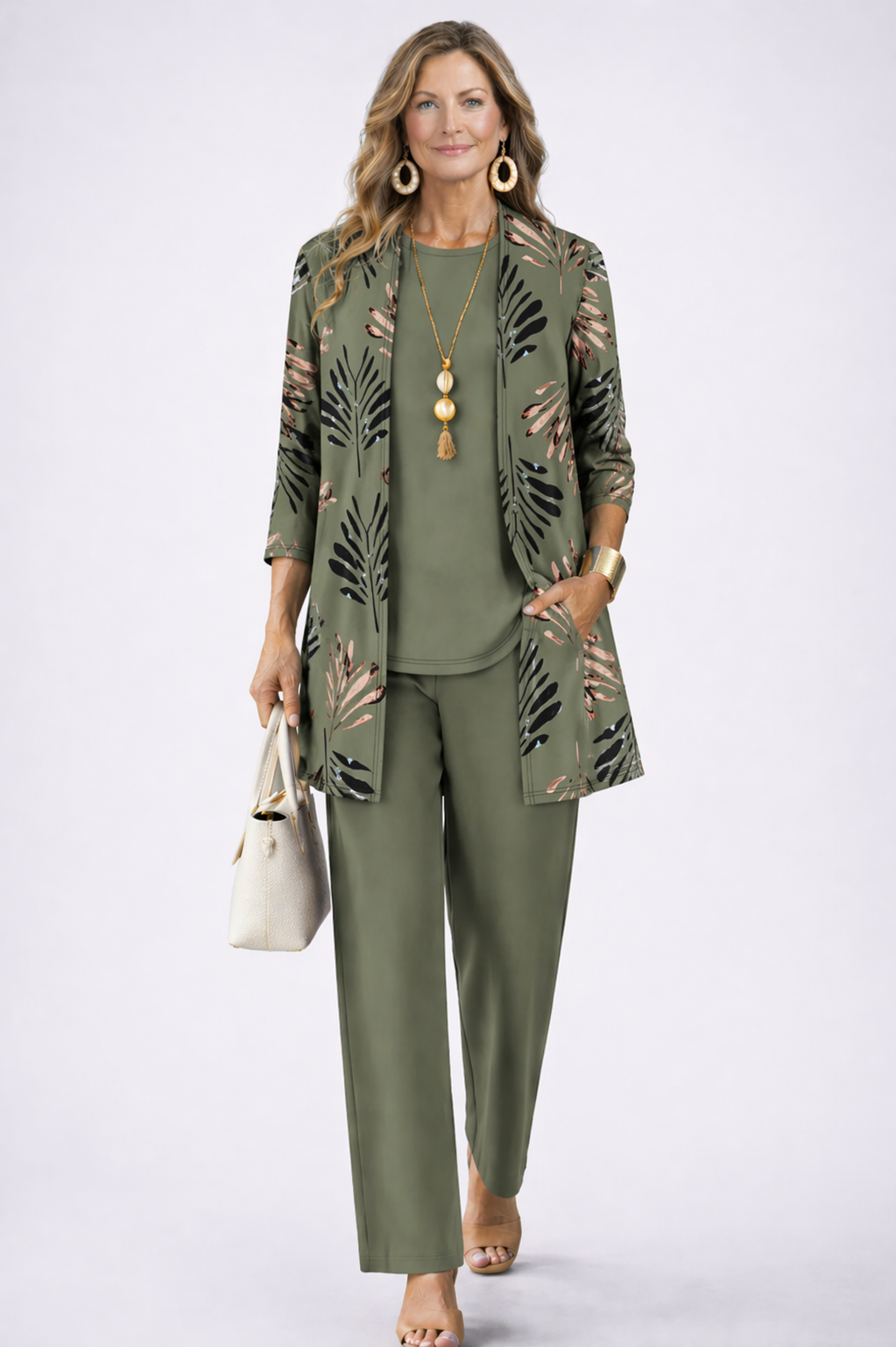 Model in Olivgrün trägt Cardigan mit Palmwedel-Print, passendes Top und weite Hose, dazu helle Handtasche 1