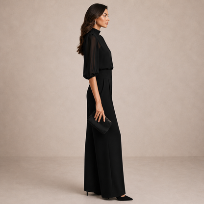 Seitenansicht in Schwarz: Puffärmel der Chiffonbluse und fließender Fall der Hose mit weitem Bein, Clutch in der Hand 3