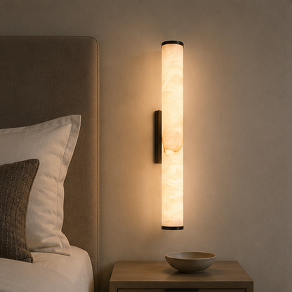 Wandlampe mit schwarzer Halterung und marmoriertem Leuchtzylinder über einem Holznachttisch mit Schale, neben dem Kopfteil eines Bettes. 9