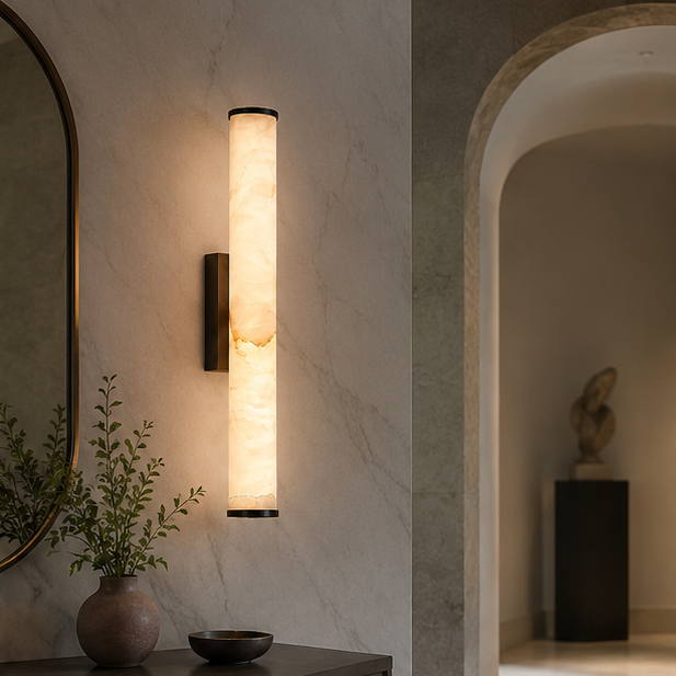 Wandlampe mit schwarzen Kappen an heller Marmorwand im Flur, daneben Spiegel, Vase mit Zweigen und ein Rundbogen mit Skulptur. 5