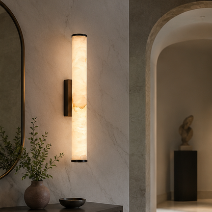 Wandlampe mit schwarzen Kappen an heller Marmorwand im Flur, daneben Spiegel, Vase mit Zweigen und ein Rundbogen mit Skulptur. 5