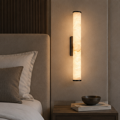 Leuchtende Wandlampe mit schwarzen Kappen über einem Nachttisch mit Schale und Büchern, neben einem gepolsterten Bett mit Kissen. 6