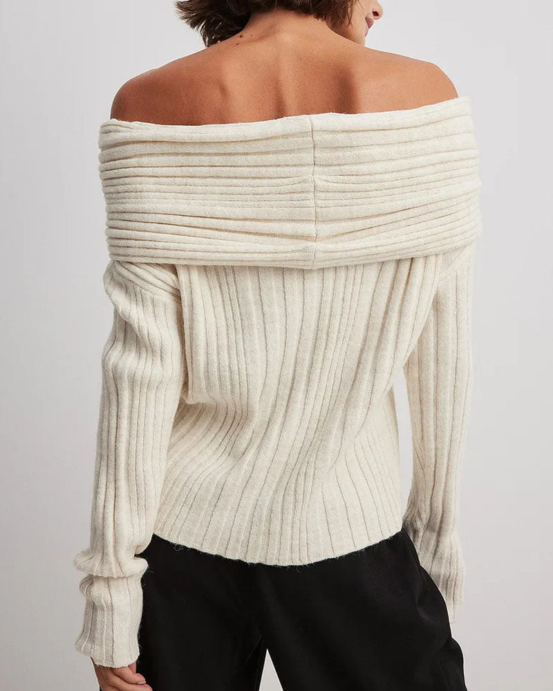 Frau trägt cremeweißen, schulterfreien Strickpullover, geripptes Design, modisch, elegant.