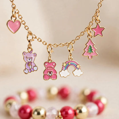 Nahaufnahme eines goldfarbenen Charm-Armbands mit rosa Anhängern wie Herz, Bär, Regenbogen, Tannenbaum und Stern 3