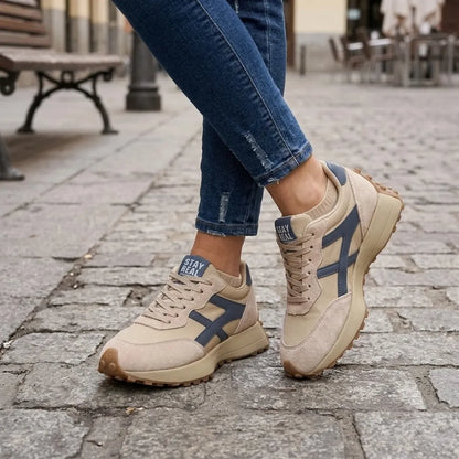 Beige Sneaker mit blauen Streifen, getragen zu Jeans auf Kopfsteinpflaster 2
