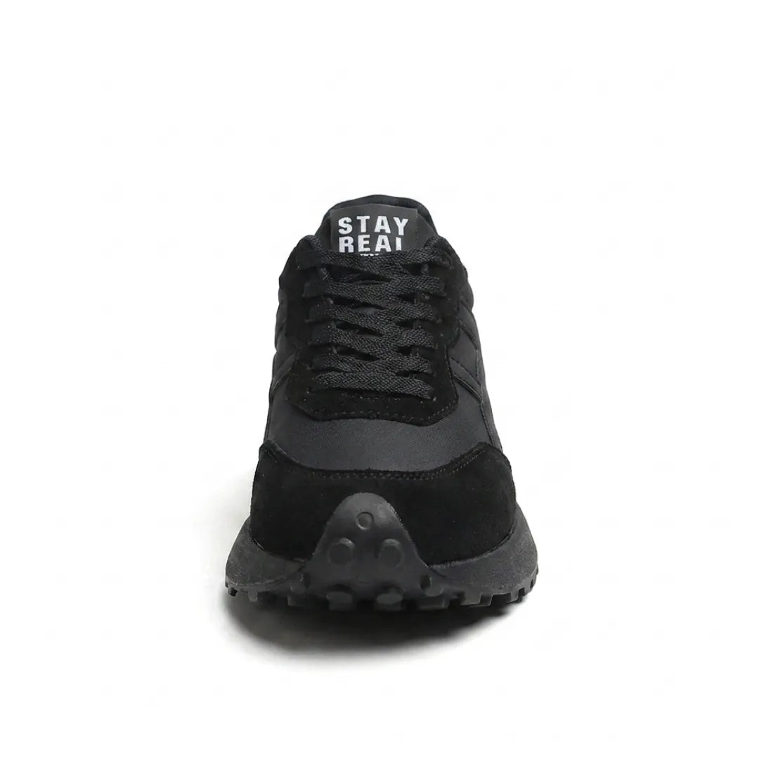 Schwarzer Sneaker von vorn mit Schnürung, Wildleder-Zehenkappe und Noppenprofil an der Sohle 9