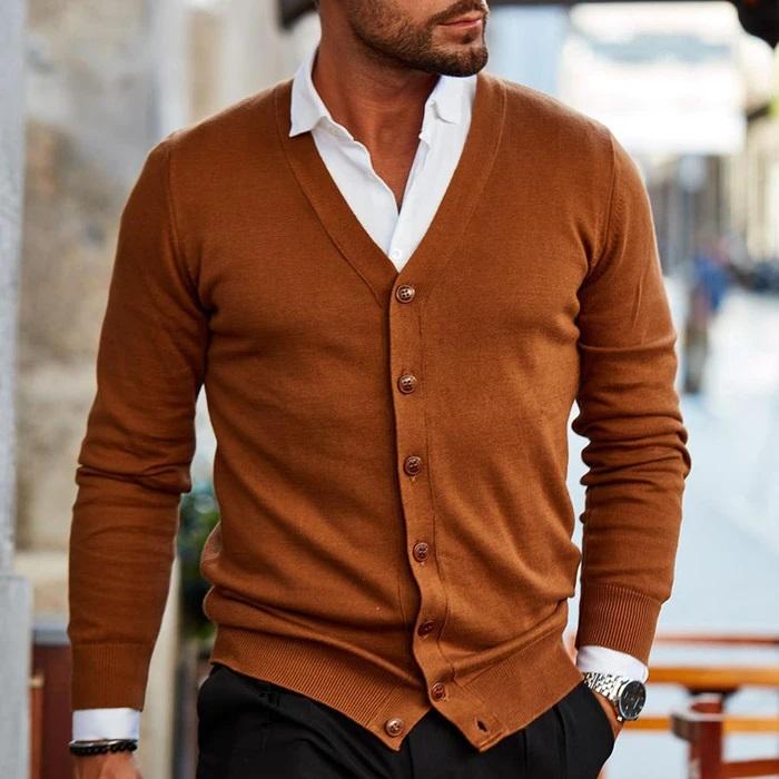 Mann trägt die Strickjacke in Karamellbraun über weißem Hemd und schwarzer Hose, Blick auf V-Ausschnitt, Knopfleiste und Bündchen. 2