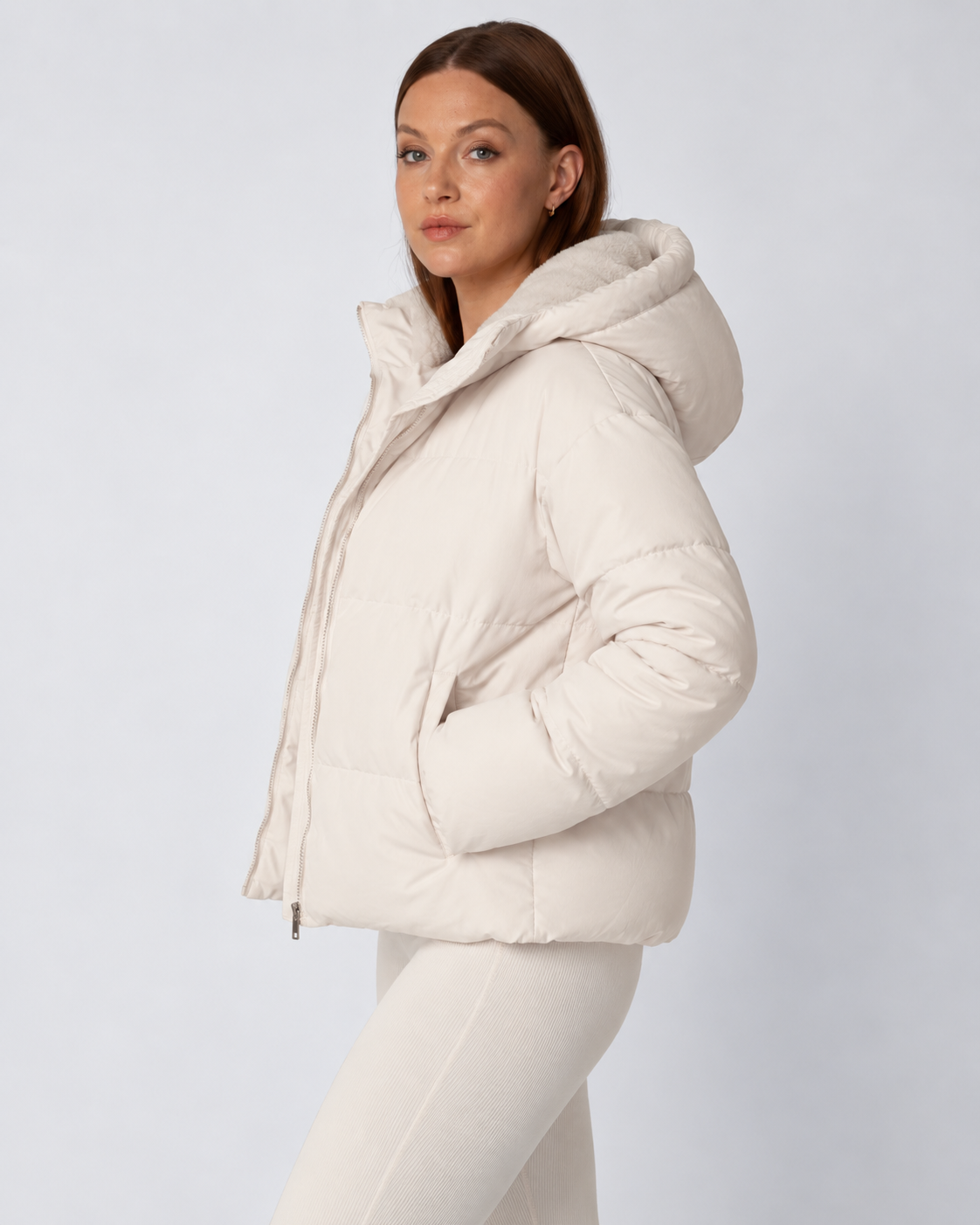 Seitenansicht der cremefarbenen Jacke mit aufgesetzter Kapuze, Hände in den seitlichen Taschen 3