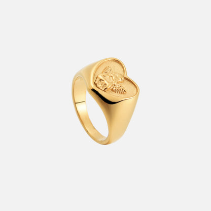 Dasselbe goldfarbene Herzring-Modell von oben schräg fotografiert, mit Blick auf die Ringschiene und das Engelrelief. 2