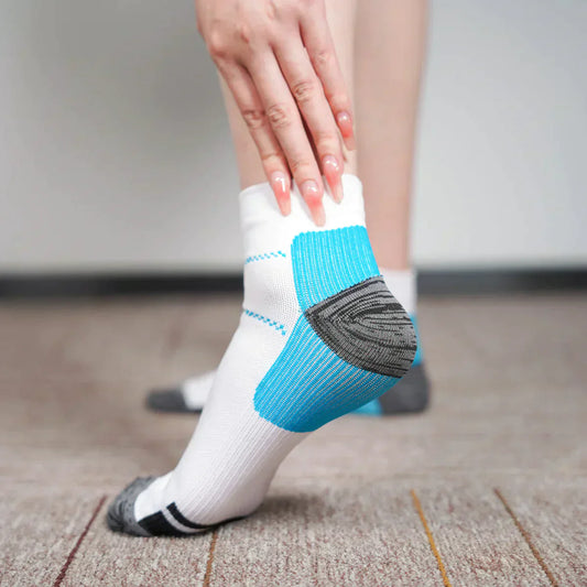 Weiße Sportsocken mit blauen und grauen Akzenten, getragen auf Teppichboden.