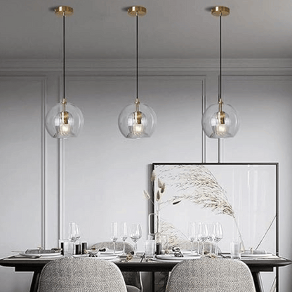Drei moderne Glas-Pendelleuchten über Esstisch, goldene Akzente, elegantes Esszimmer-Design.