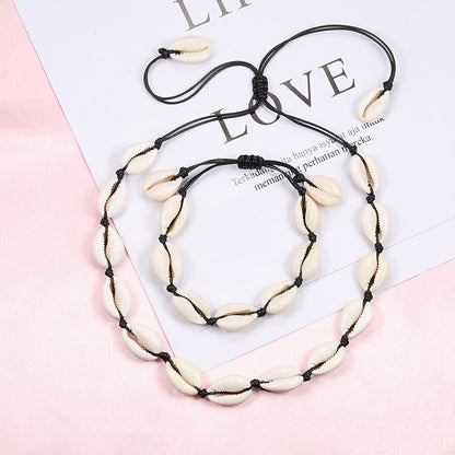 Halskette und Armband Set aus Naturmuscheln auf schwarzer Kordel, modisches Schmuckdesign.